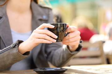 Fototapeta na wymiar Woman hands holding a coffee cup on a cafe terrace