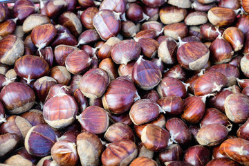Fall and winter rustic dessert sweet roasted chestnuts in a large metallic bowl, available for sale at a street food market festival, seasonal food photograph with selective focus