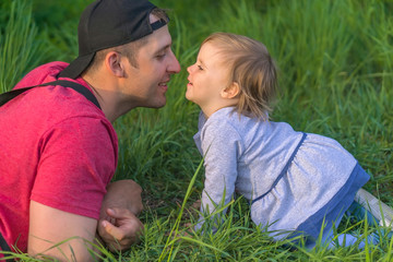 Fototapeta premium Fathers day. Father and his smiling happy daughter have fun at green park