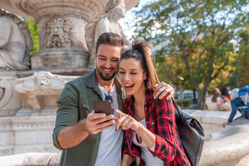 A happy couple looking at their phone in a European city