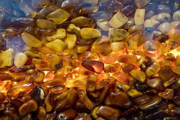 Amber grains with backlight illumination as texture or background. heap of amber stones backlightet glowing. Small raw amber. amber stones rectangular lie on a flat surface