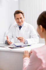 smiling ent physician talking to child during consultation