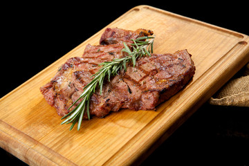 Grilled beef steak with rosemary. Grilled striploin sliced steak. Juicy thick grilled T-bone beef...