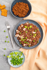 Quinoa porridge with green pea and chicken on ceramic plate on a gray concrete background. Top view, close up.
