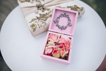 Naklejka na ściany i meble Pink wooden box with roses and wedding rings inside is on the round white table