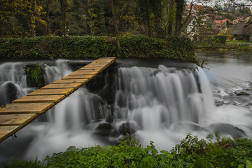 Naklejka premium Man made cascades on the river of Krka close to Zuzemberk in slovenia, used to power an old wood sawmill. Visible wooden bridge over the water.