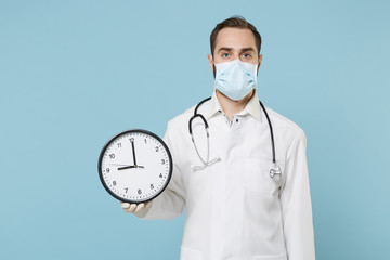 Male doctor man in medical gown sterile face mask gloves isolated on blue background in studio....