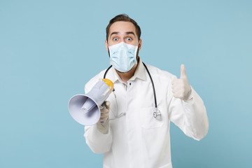 Excited male doctor man in medical gown face mask gloves isolated on blue background. Epidemic...