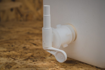 Petcock or tap on the bottom of a white transparent jerry can for liquids or water.