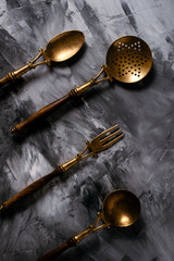Photo of the vintage old wonderful brass metal with wood hand cutlery set on a dark background with dry leaves