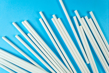 A lot of white paper tubes are scattered randomly on a blue background. The view cocktail tube texture. Zero waste