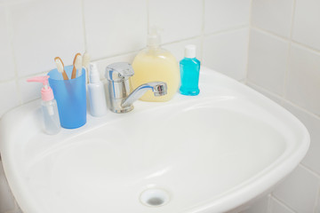 bathroom with washbasin with soap dispenser and cosmetics bottles with toothbrush