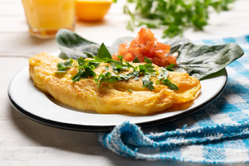 French omelette with tomato and spinach on white background