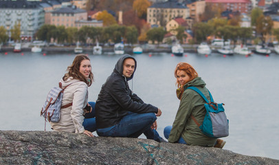 Group of tourists is posing on the Skinnarviksberget lookout viewpoint, way above the Stockholm. Cityscape of stockholm is seen in the background.