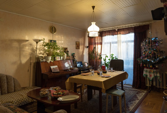 Interior of typical simple cozy living room decorated for Christmas dinner with arranged table and retro styled Christmas tree