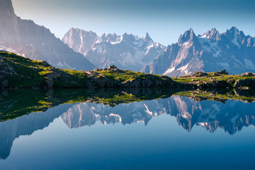 Crystal lake reflecting snowy mountains in bright day
