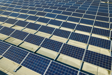 Aerial view of many photo voltaic solar panels mounted of industrial building roof.