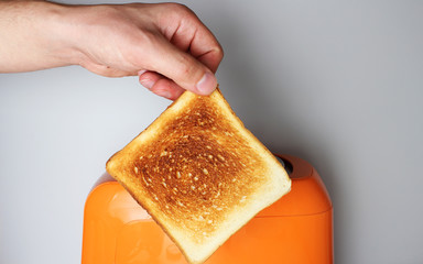 hand toast and orange toaster on a light background