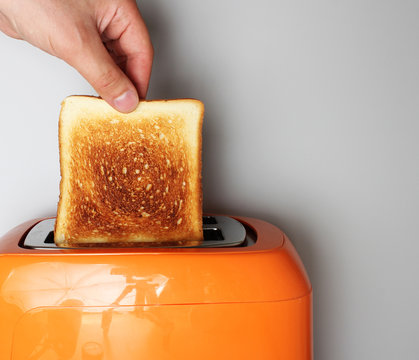 hand toast and orange toaster on a light background