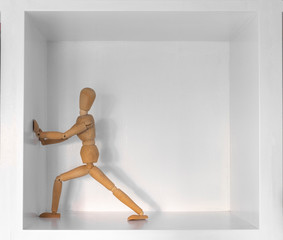 Boneco manequim em madeira empurrar parede branca