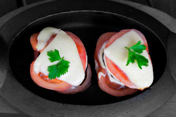 Baked eggplant with tomato, cheese and cilantro leaf in cast iron pan