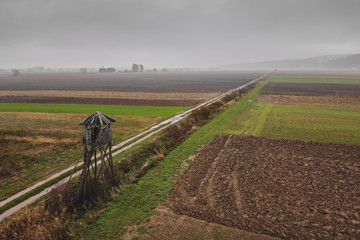 Hunter turret or cottage on a large field on a misty day. Hunting tower or lookout between the...