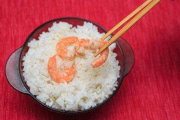 Shrimp with rice in a brown plate with chopsticks, sharpness in the foreground.