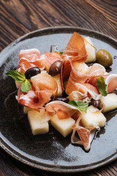 From above delicious slices of smoked salmon with vegetables and pickled olives on plate