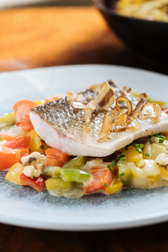 From above of fillet fish with small square slices of peppers on plate in restaurant