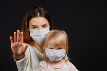 a girl in a mask shows a stop gesture fearing for the health of people