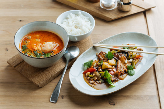 Top view of colorful vegetables in oval plate with chopsticks on wooden table with spicy seafood soup and with of boiled rice