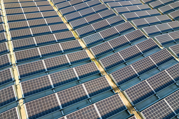 Aerial view of many photo voltaic solar panels mounted of industrial building roof.