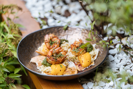 From above tasty fresh fried eggs with shrimps covered by herbs in pan on wooden table in garden