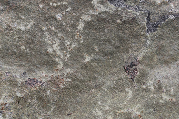 Closeup of a big solid stone in white, grey and black tones. In this photo you can see the rustic texture of the uneven surface of the rock in detail. Perfect grungy background image. Color photo.