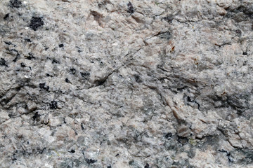 Closeup of a big solid stone in white, grey and black tones. In this photo you can see the rustic texture of the uneven surface of the rock in detail. Perfect grungy background image. Color photo.