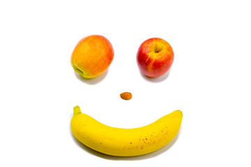 Smiley wink face with apples an almond and a banana on white background