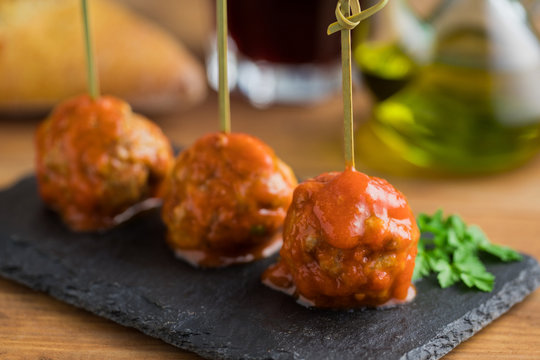 Tasty meat balls with tomato sauce bonded with bamboo sticks on flat board on table