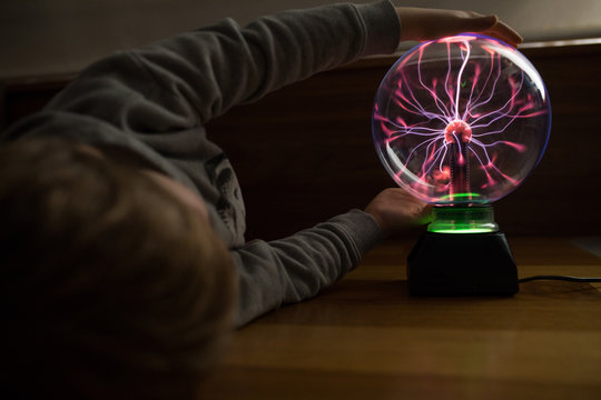 Boy looking at mysterious glass lightening lamp on table