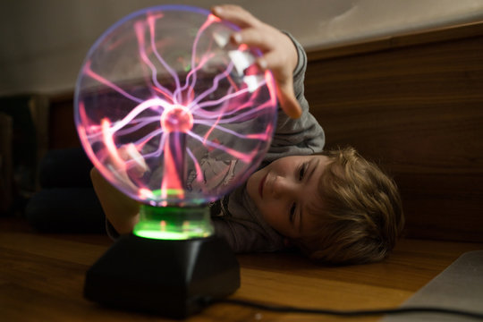 Boy looking at mysterious glass lightening lamp on table