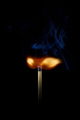 A burning match on a black background