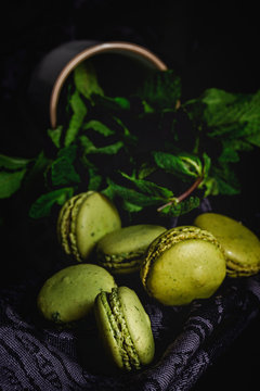 Homemade green macarons green with mint on dark background. Dark food.