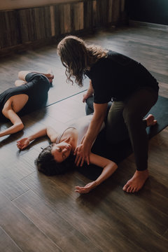 From above diligent female instructor in sportswear teaching group of sporty people to do ardha jathara parivartanasana pose lying on sports mats in modern workout room