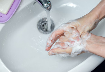 Fototapeta premium Woman washing hands with soap under the faucet in bathroom. Step by step picture instructions for thorough medical procedure. Step 7, wash the right thumb.