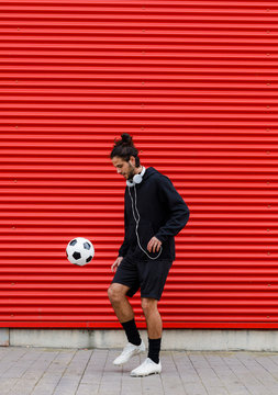 Man playing soccer ball on street