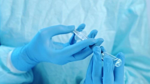 Infectious disease prevention. Clinical vaccination. Doctor hands filling syringe from ampoule.