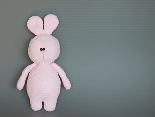 Pink knitted bunny on a gray background