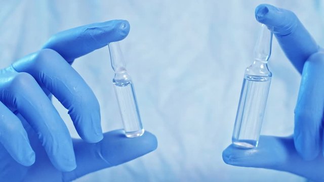 Antibiotic medications. Infectious disease treatment. Doctor hands in gloves comparing two ampoules.