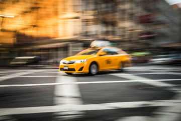 Gelbes Taxi in Ney York auf einer Kreuzung in Bewegung.