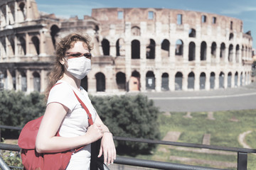 COVID-19 coronavirus in Italy, woman in face medical mask next to empty Colosseum in Rome. Tourist landmarks closed due to corona virus outbreak.