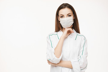Beautiful female doctor or nurse wearing protective mask and medical gown posing on white background with copy space, isolated. Young woman in medical uniform. Healthcare concept